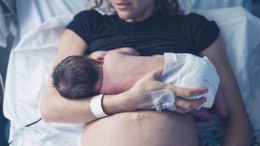Mother holding newborn after delivery in a hospital bed